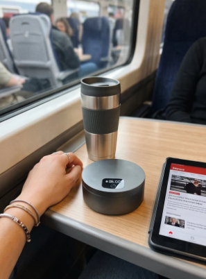 Gauge L1 Lockbox on a train tray table beside a travel mug