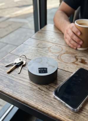 Gauge L1 Lockbox on a café table next to keys and a phone